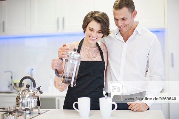 Couple pouring a coffee from french press in kitchen
