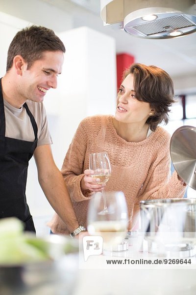 Couple drinking glass of white wine in kitchen