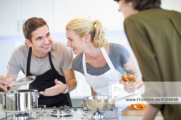 Mid adult man and friends preparing food in kitchen
