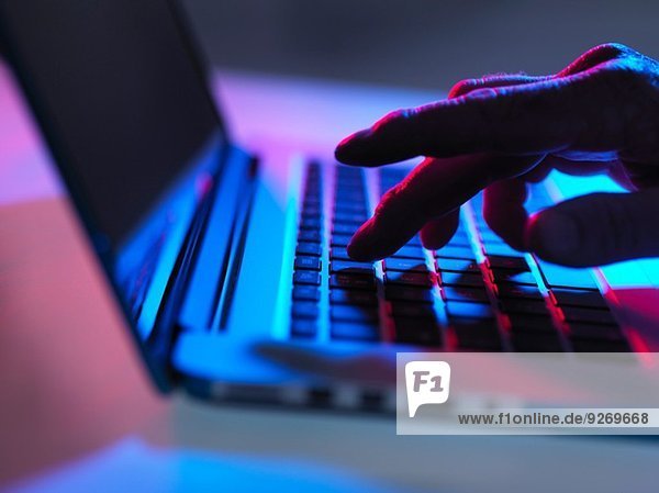 Silhouette der männlichen Hand Tippen auf Laptop-Tastatur bei Nacht