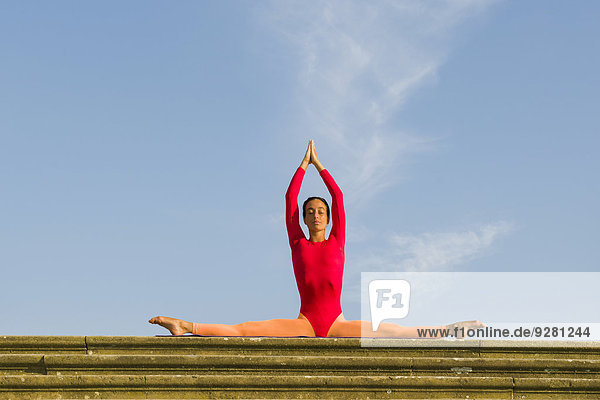 Junge Frau praktiziert Hatha-Yoga im Freien  in Samakonasana-Haltung  Pose des rechten Winkels  Seitwärtsspagat