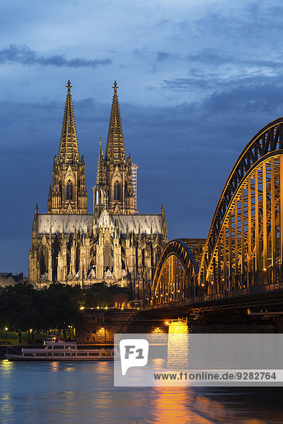 Kölner Dom mit Hohenzollernbrücke in der Abenddämmerung  vorne Rhein  Köln  Nordrhein-Westfalen  Deutschland