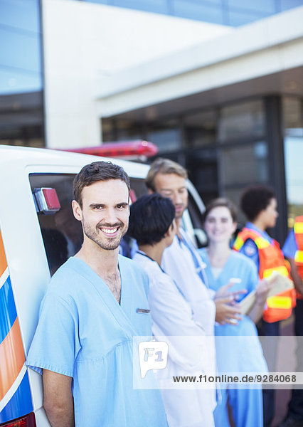 Krankenschwester lächelt mit dem Krankenwagen auf dem Krankenhausparkplatz