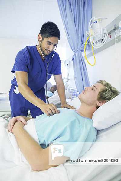 Krankenschwester untersucht Patientin im Krankenhauszimmer