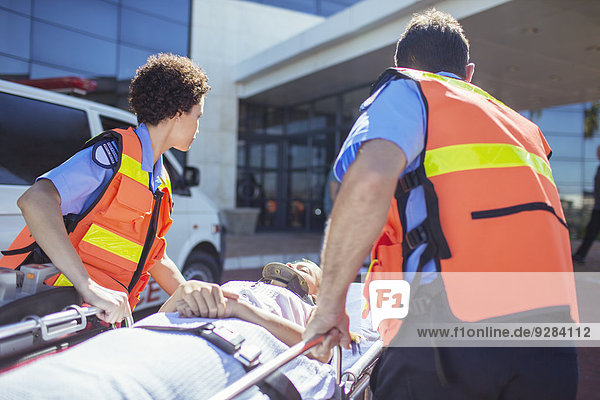 Paramedics wheeling patient in hospital parking lot