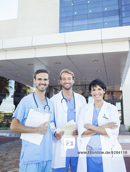 Ärzte und Krankenschwester lächeln außerhalb des Krankenhauses