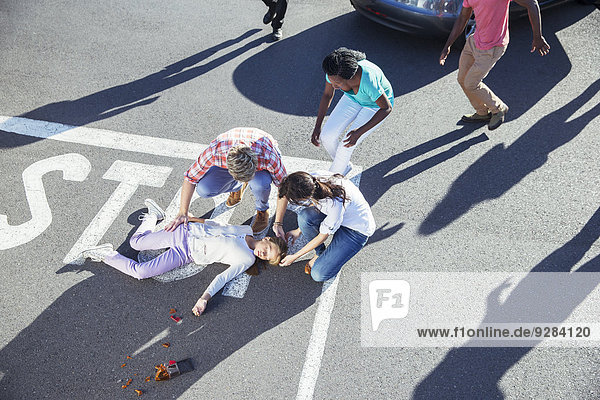 Menschen untersuchen verletztes Mädchen auf der Straße