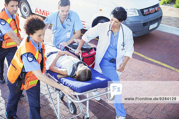 Doctor  nurse and paramedics wheeling patient on stretcher