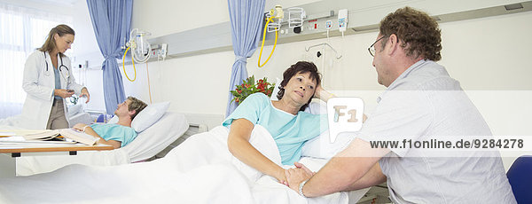 Mann im Gespräch mit Frau im Krankenhauszimmer