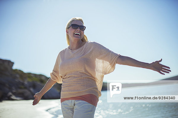 Ältere Frau lächelt in der Sonne am Strand