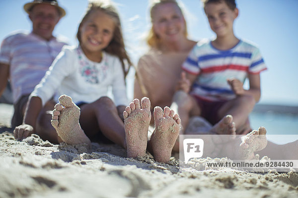 Family sitting together with feet in sand