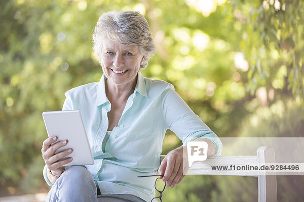 Ältere Frau mit digitalem Tablett im Freien