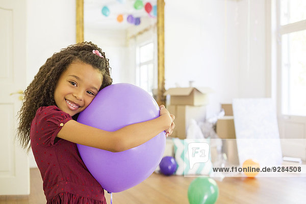 Young girl hugging purple balloon