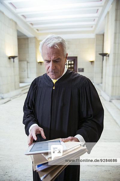 Richter mit digitalem Tablett im Gerichtsgebäude