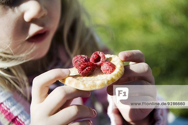 Girl holding pancake with raspberries
