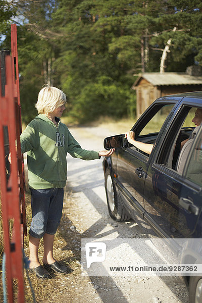 Boy opening gate for car