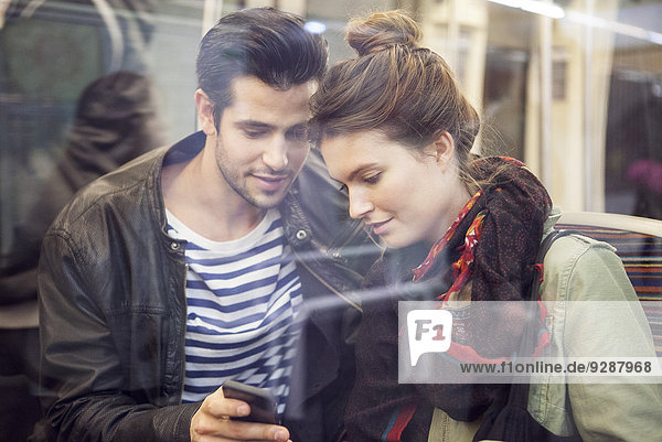 Paar in der U-Bahn schaut gemeinsam auf das Smartphone