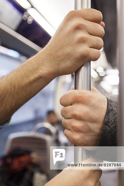 Communters on subway holding grab handle  close-up