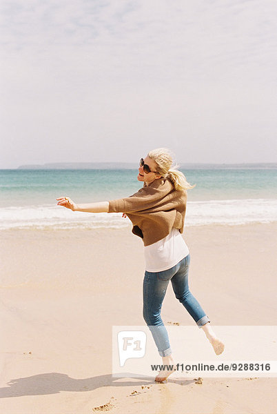 Eine Frau  die barfuß auf dem Sand tanzt und sich durch Bewegungen ausdrückt.