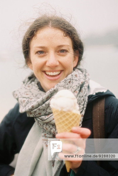 Eine Frau hält ein Eis in einer Waffel und lacht.