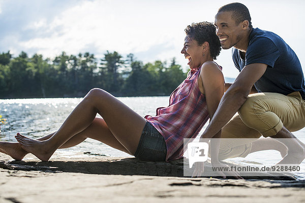 Ein Ehepaar nahe beieinander an einem See im Sommer.