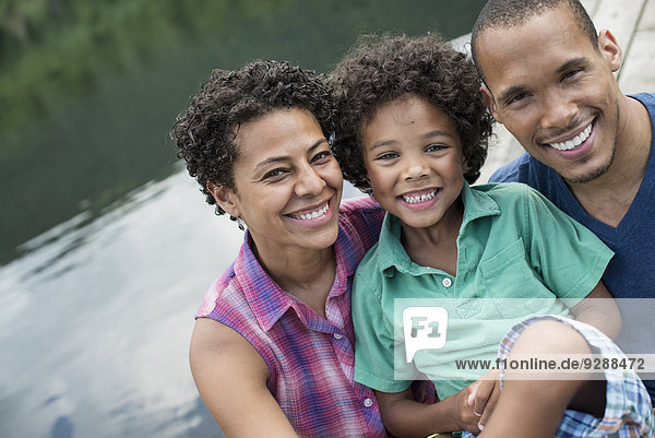 Eine Familie  Eltern und ein kleiner Junge  im Sommer an einem See.