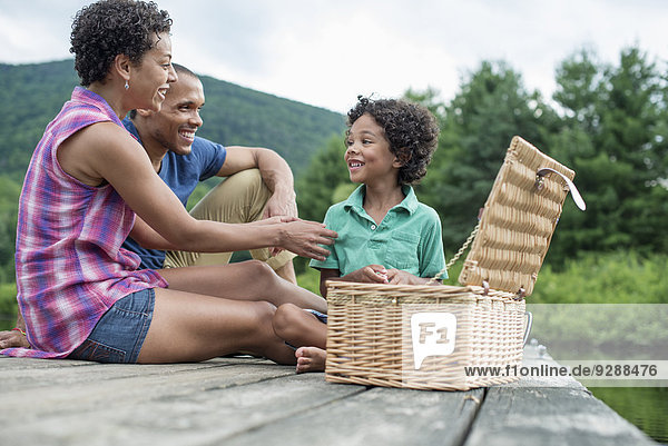 Eine Familie  die im Sommer ein Picknick an einem See macht.