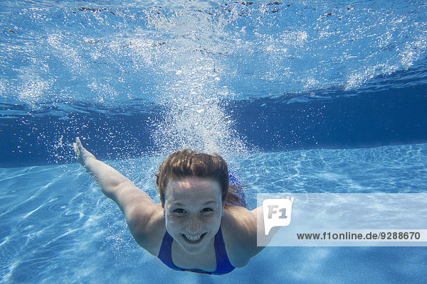 Ein junges Mädchen mit langen Haaren  das sich im Wasser auffächert und unter Wasser schwimmt.