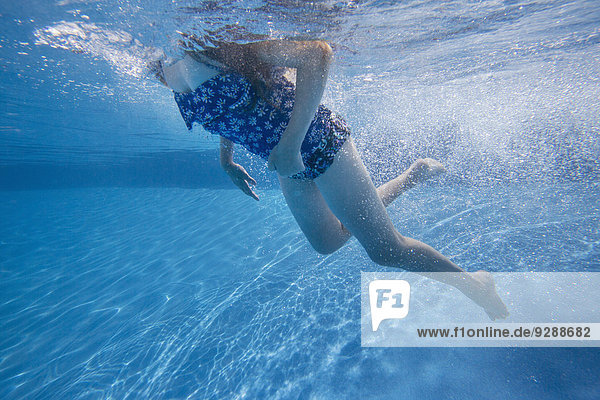 A child swimming under water in a swimming pool.