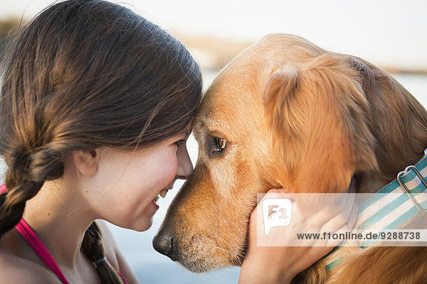 Ein junges Mädchen und ein Golden Retriever Hund  Nase an Nase.