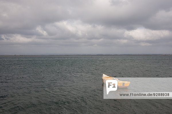 Ein kleines Holzboot  das im offenen Wasser vor der portugiesischen Küste vor Anker liegt.