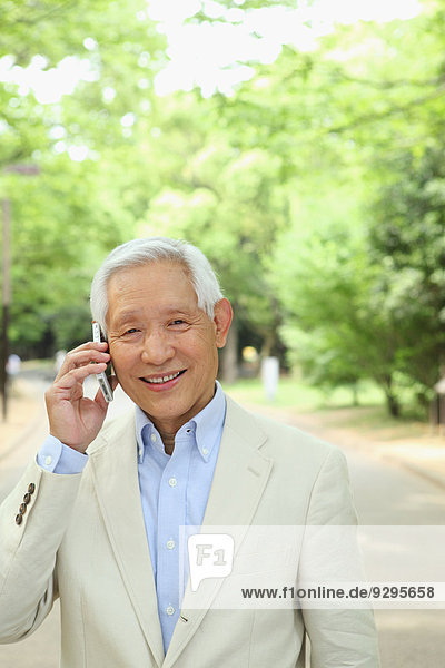 Senior adult Japanese man with smartphone in a park