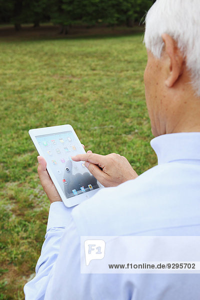 Senior adult Japanese man with tablet in a park
