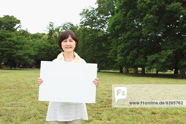 Senior adult Japanese woman with whiteboard in a park