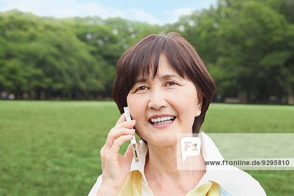 Senior adult Japanese woman with smartphone in a park