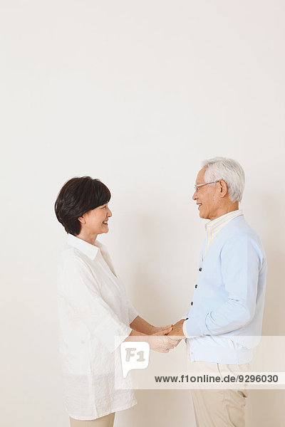 Senior adult Japanese couple against white wall