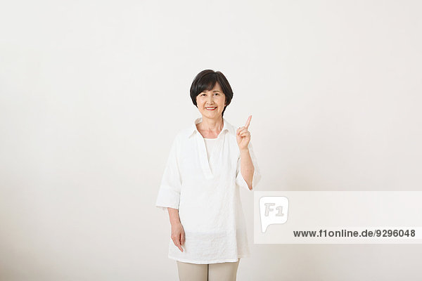 Senior adult Japanese woman against white wall