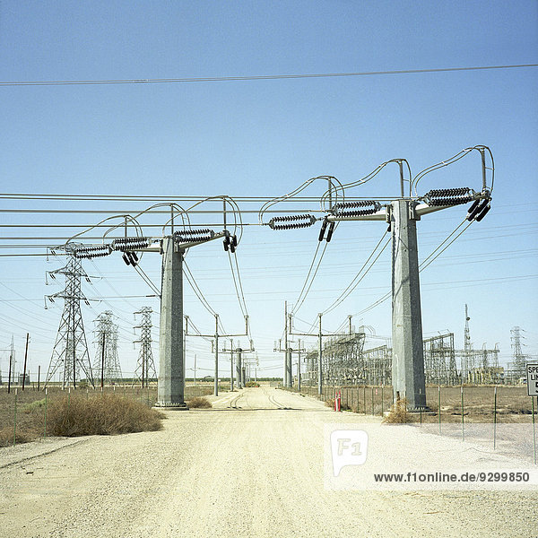Strommasten entlang eines Feldweges in der Wüste