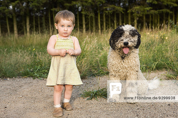 Kleines Mädchen stehend mit Portugiesischem Wasserhund  Portrait