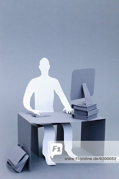 Zuversichtlicher Papierunternehmer am Schreibtisch über grauem Hintergrund