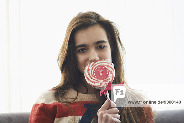 Porträt eines romantischen Mädchens  das den Mund mit Lolli bedeckt.