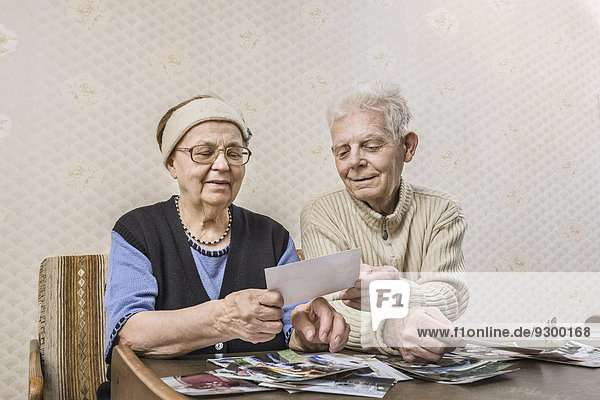 Seniorenpaar beim Durchblättern von Bildern zu Hause