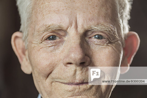 Close-up portrait of smiling senior man over colored background
