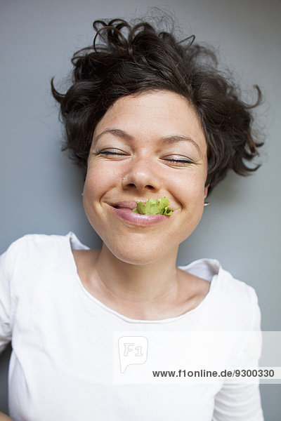 Eine Frau isst Salat auf grauem Hintergrund