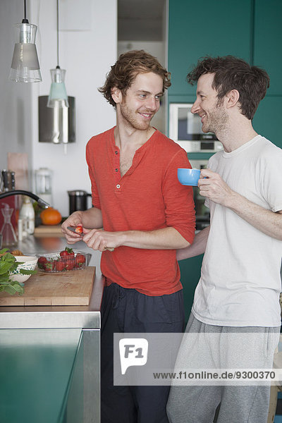 Happy gay couple looking at each other in kitchen