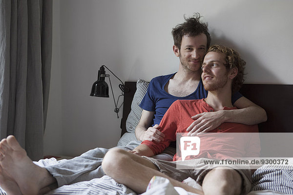 Loving gay couple relaxing in bed at home
