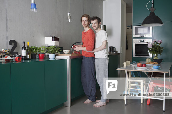 Full length portrait of young gay couple in kitchen