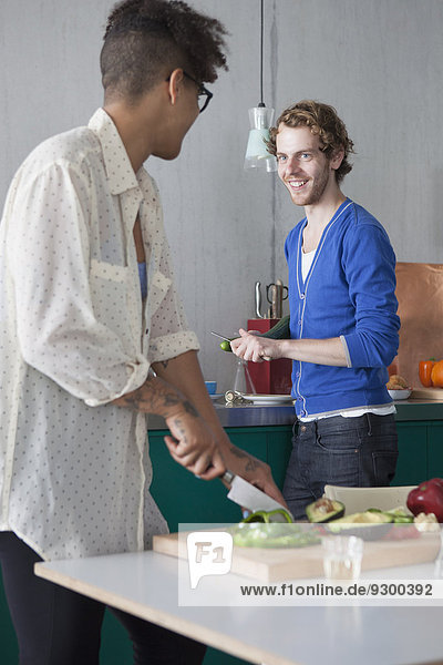 Lächelnder Mann beim Kochen mit Freundin in der Küche