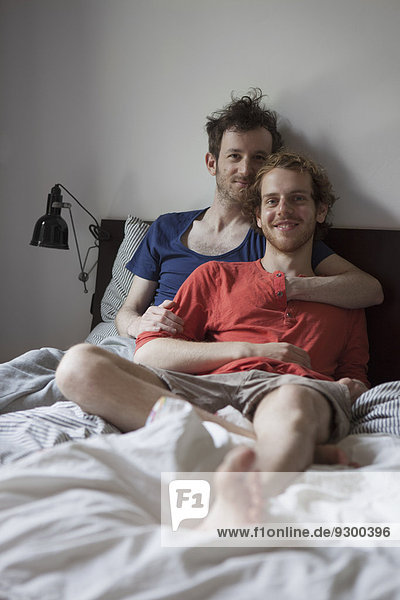 Portrait of romantic gay couple relaxing on bed at home