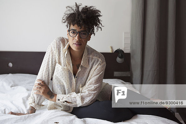 Porträt einer selbstbewussten Frau  die zu Hause auf dem Bett sitzt.